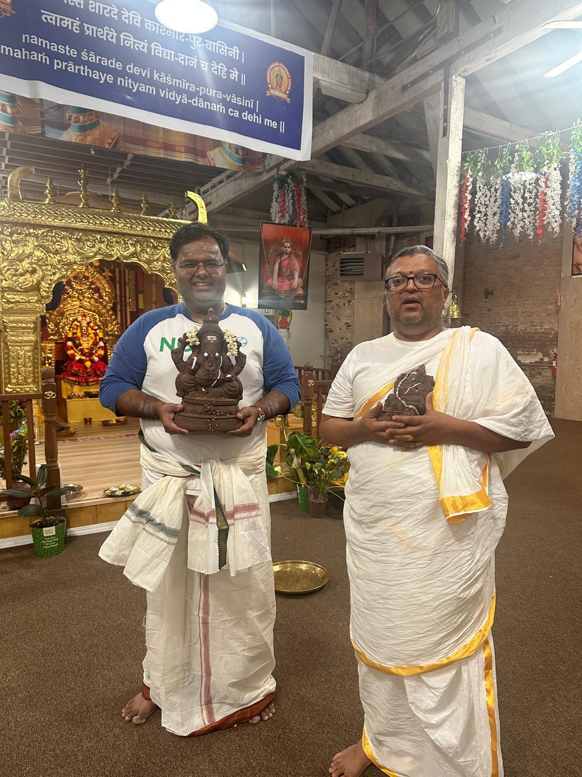 Two priests in traditional attire holding sacred items